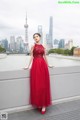 A woman in a red dress standing on a bridge.