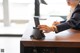 A woman sitting at a desk using a cell phone.