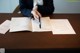 A woman sitting at a table signing a document.