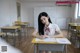 A woman sitting at a desk in a classroom.