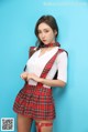 A woman in a red plaid skirt and suspenders posing for a picture.