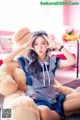 A woman sitting on the floor next to a teddy bear.