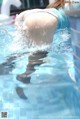 A woman in a blue bikini is swimming in a pool.