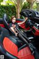 A woman sitting in the driver's seat of a red and black car.