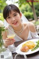 A woman sitting at a table with a plate of food and a glass of orange juice.