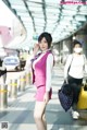 A woman in a pink suit talking on a cell phone.