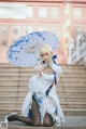 A woman in a white dress holding an umbrella.