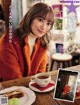 A woman sitting at a table with a cup of coffee.