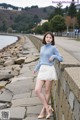 A woman in a blue sweater and white skirt posing for a picture.