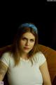 A woman with a bandana on her head sitting on a couch.