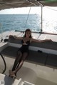 A woman in a black bathing suit sitting on a boat.