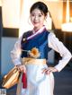 A woman in a blue and white hanbok holding a flower.