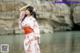 A woman in a pink kimono standing by a body of water.