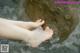 A woman's feet in the water with a rock in the background.