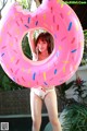 A woman in a bikini holding a pink donut shaped pool float.