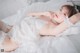 A woman laying on a bed in a white lingerie.