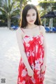 A woman in a red dress standing on a beach.