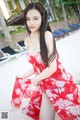 A woman in a red dress sitting on a beach.