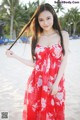 A woman in a red dress standing on a beach.