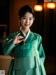 A woman in a green hanbok poses for a picture.