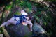 A couple of women laying on top of a rock in the woods.