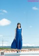 A woman in a blue dress standing on a roof.