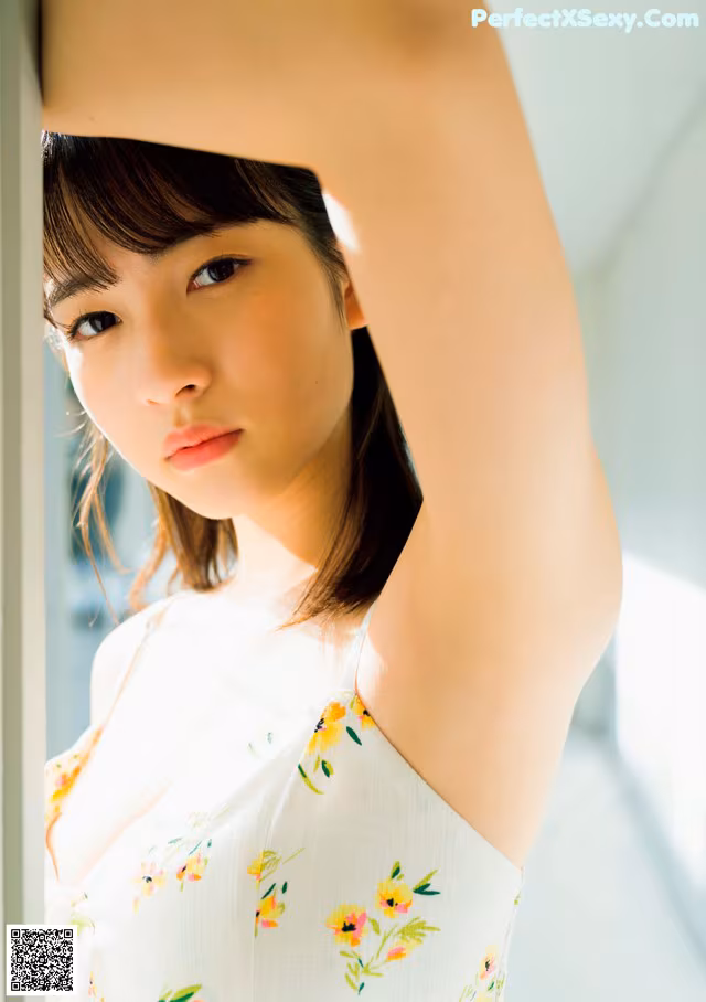 A woman in a white dress leaning against a window.