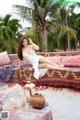 A woman in a white dress sitting on a colorful couch.