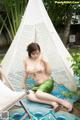 A woman sitting on the ground in front of a teepee.