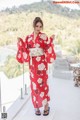 A woman in a red kimono standing on a balcony.